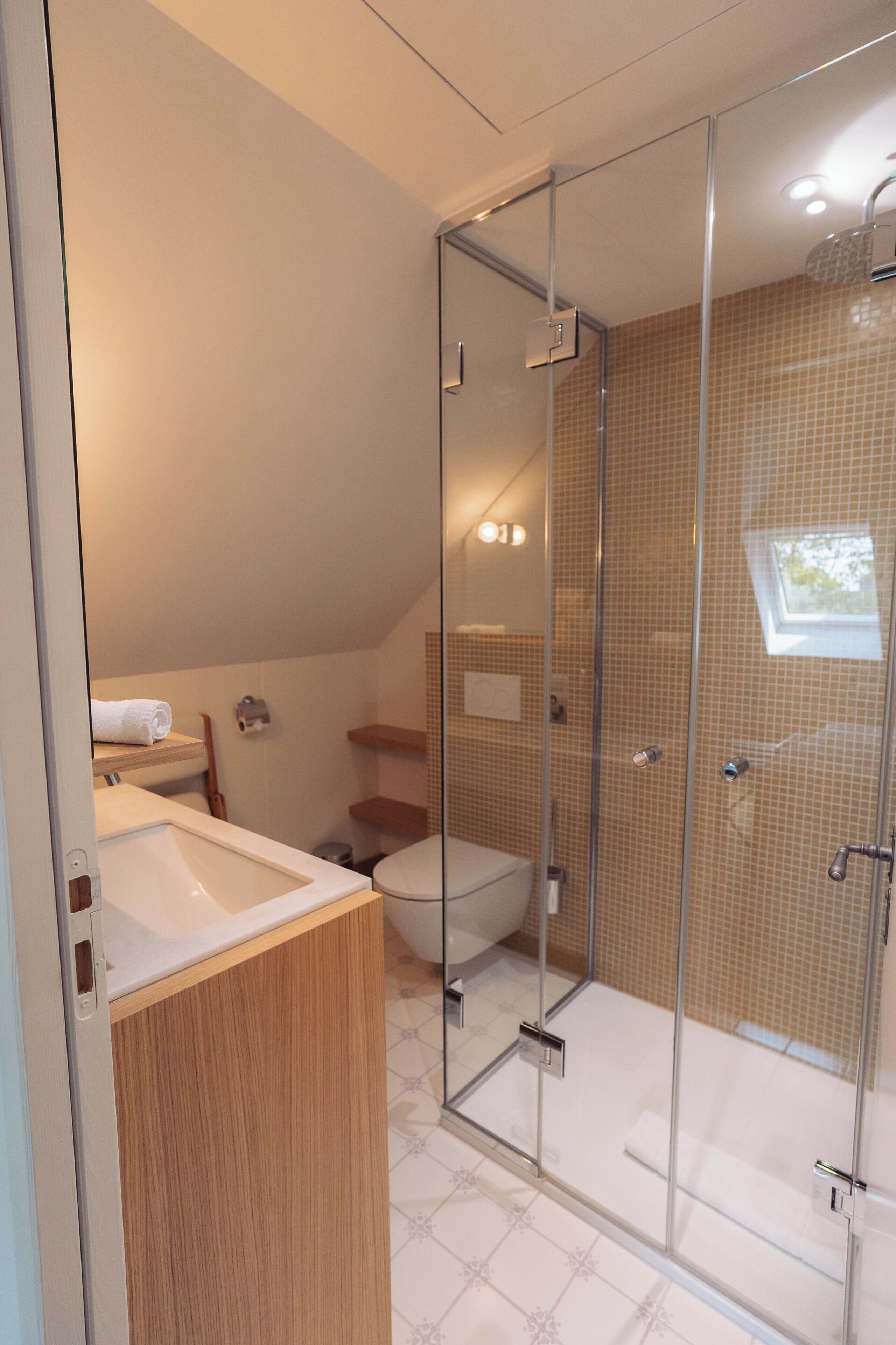 Un baño moderno con cabina de ducha de vidrio, un lavabo blanco y un inodoro.