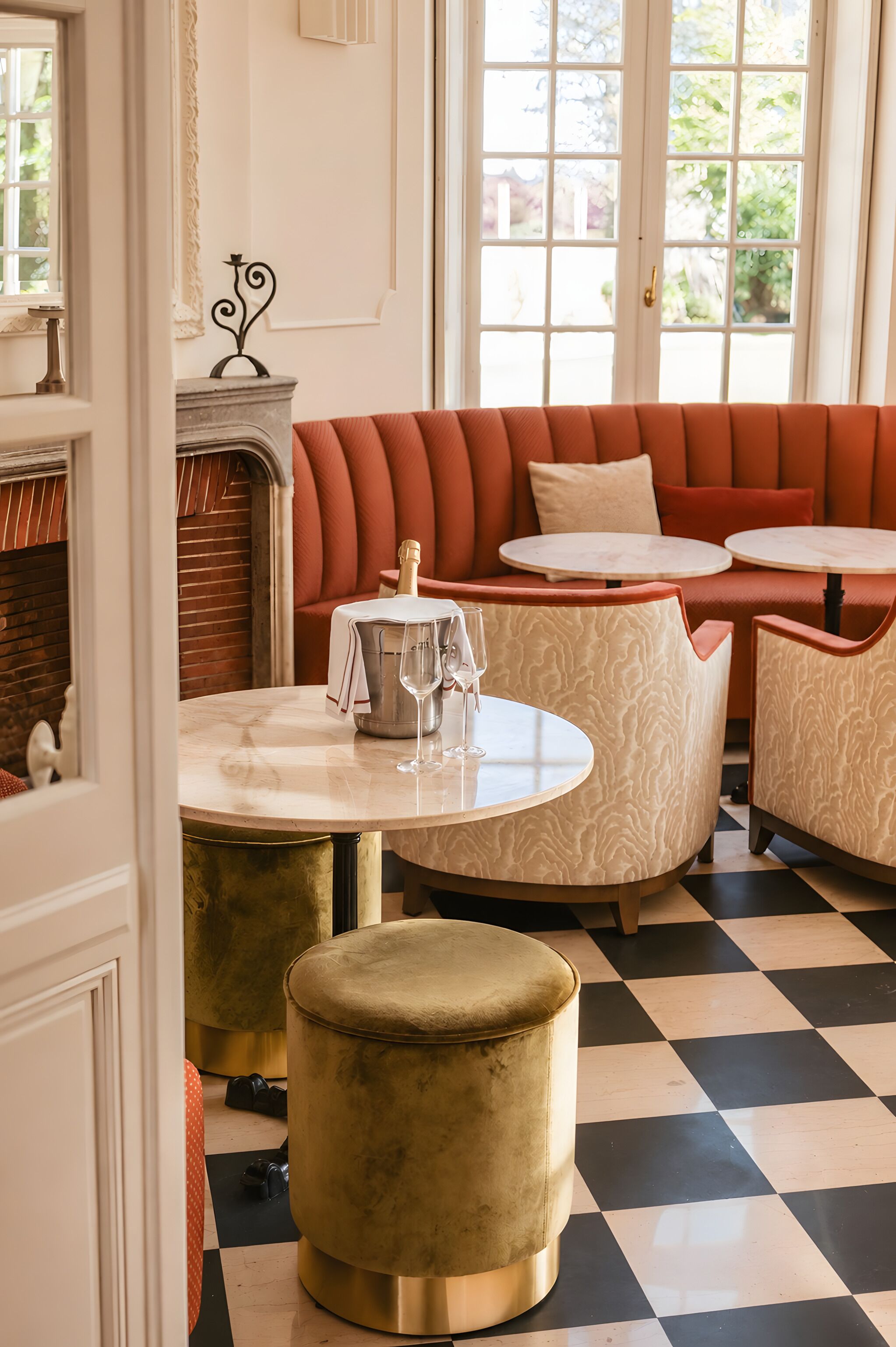 A room with a checkered floor, a sofa, two round tables, and a fireplace.