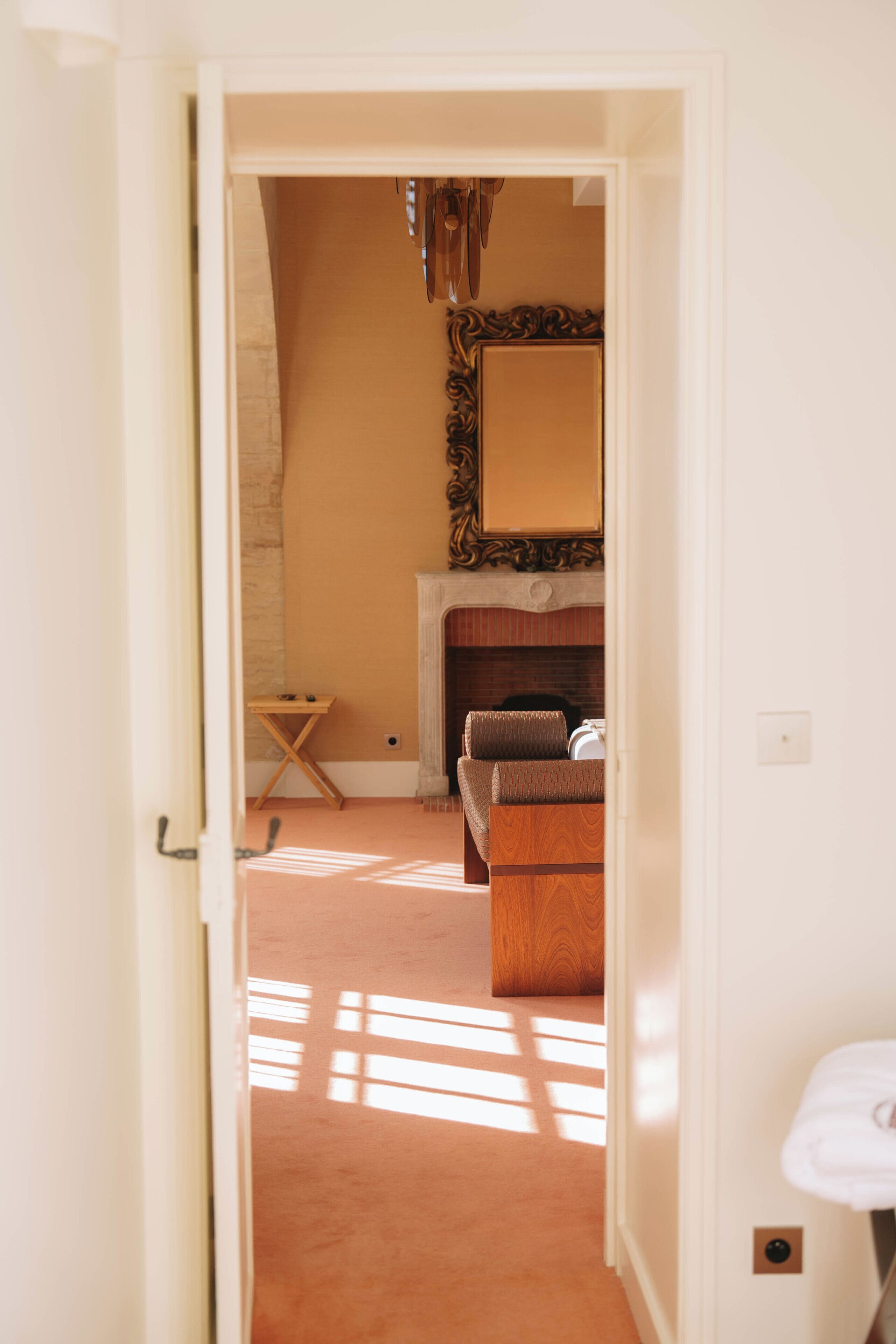A hallway leading to a room with a fireplace, a mirror, and a sofa.