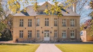 Un grand bâtiment historique à la façade symétrique, doté de nombreuses fenêtres et d’une entrée centrale.