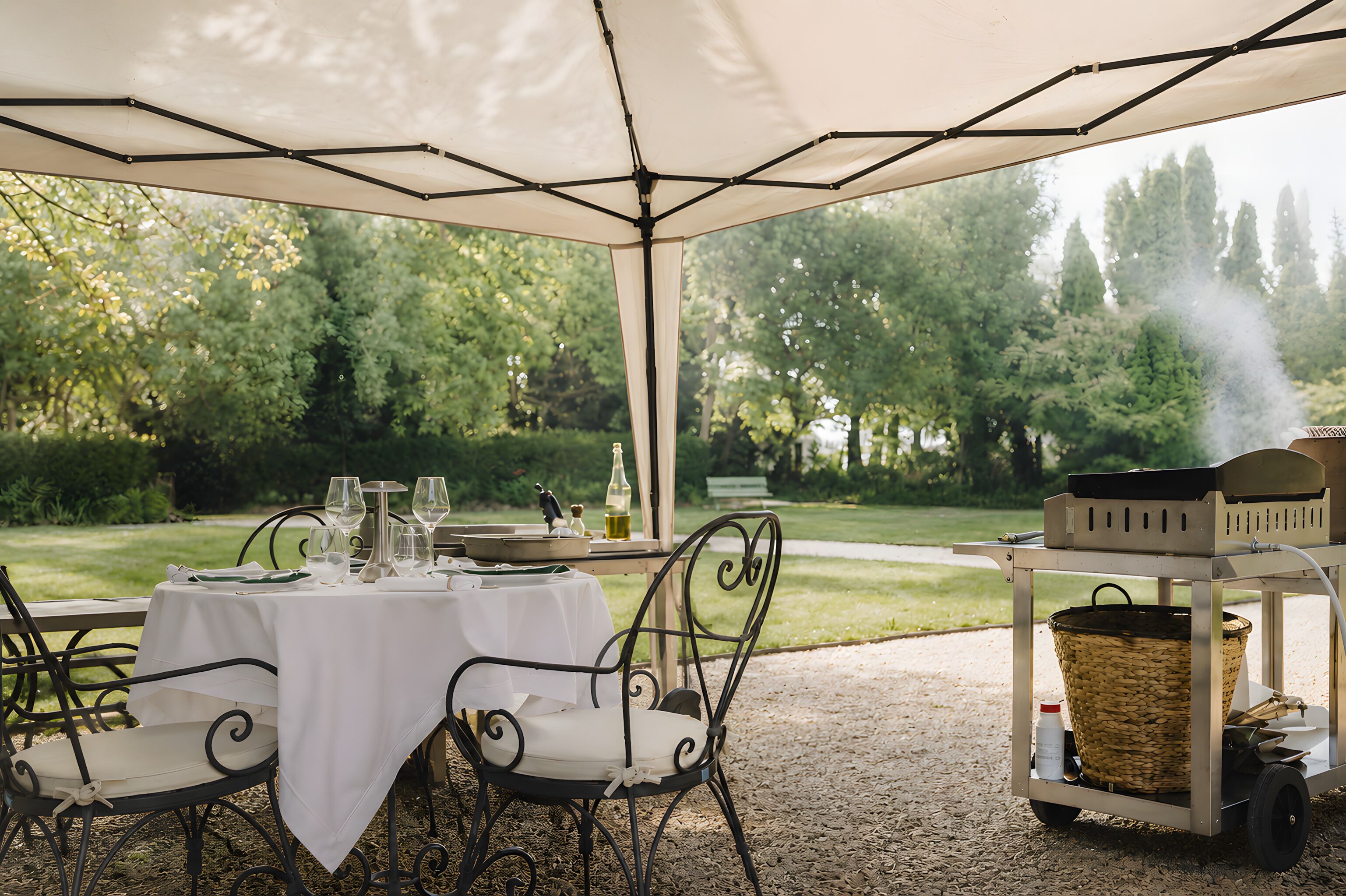 Un espacio al aire libre para comer con mesas y sillas bajo una pérgola, rodeado de follaje y árboles.
