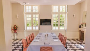 Une salle de conférence avec une longue table, des chaises et un écran de télévision.