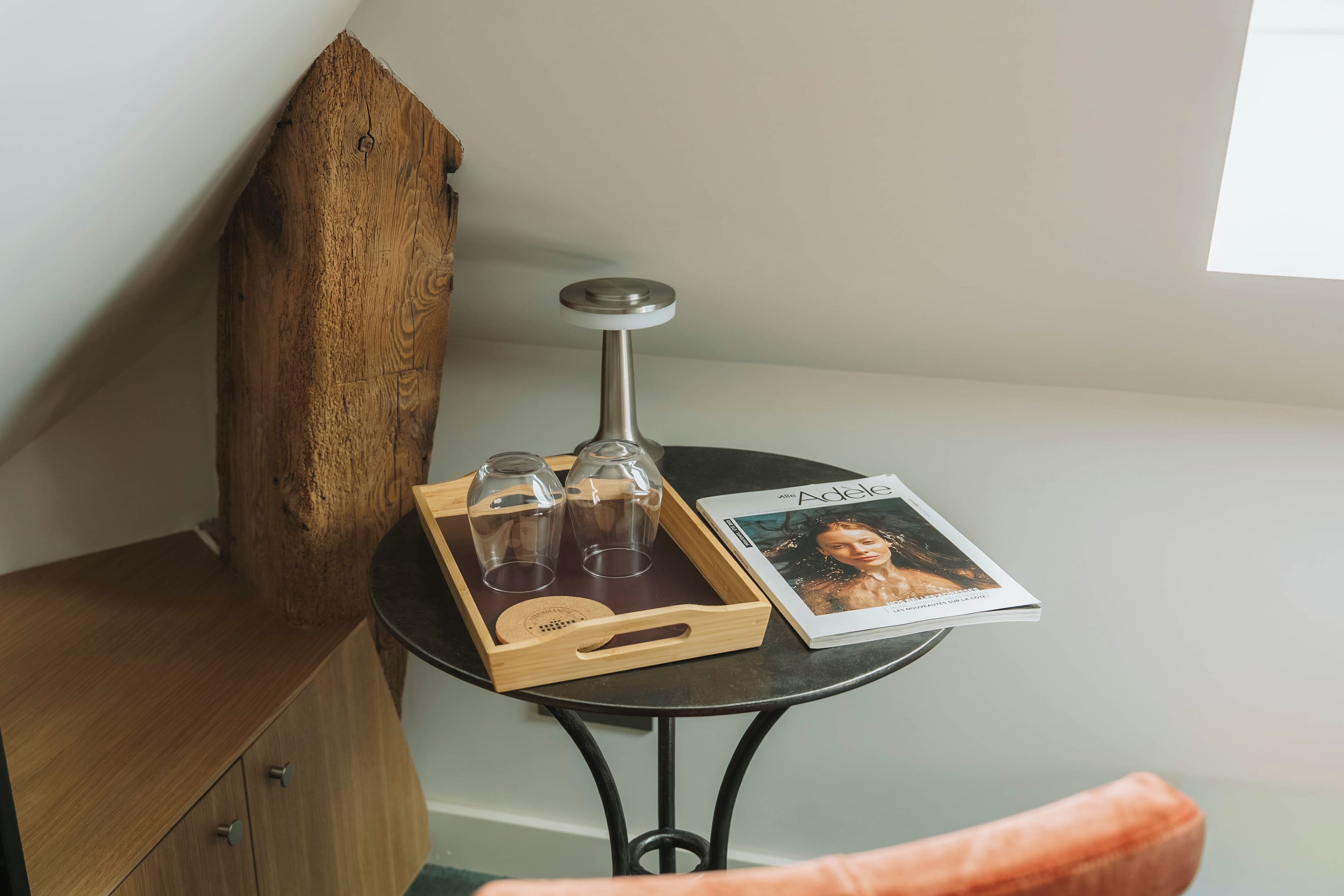 A small table with a magazine, a wooden object, and a tray with glasses.