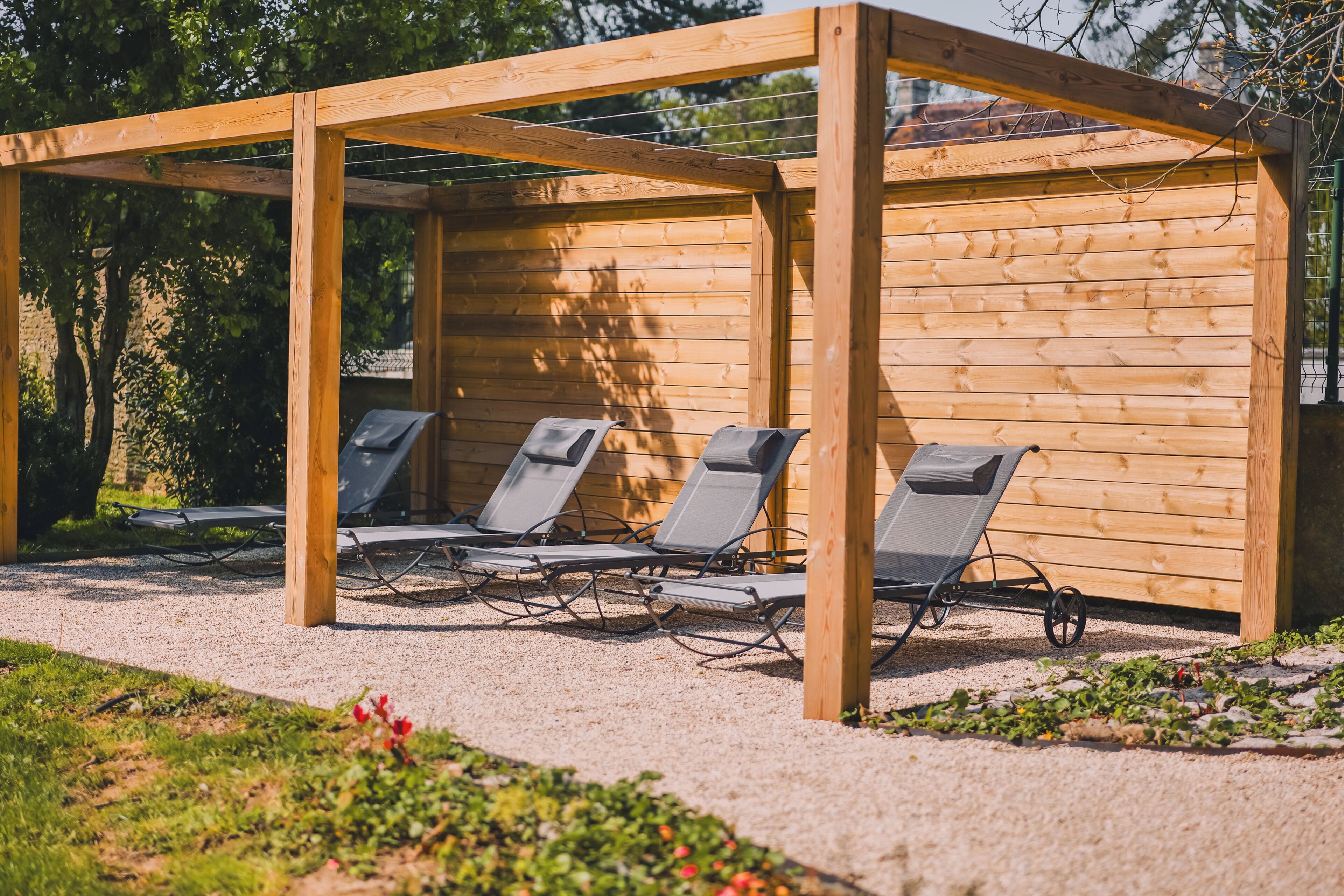 Una pérgola de madera con cuatro sillones de descanso.