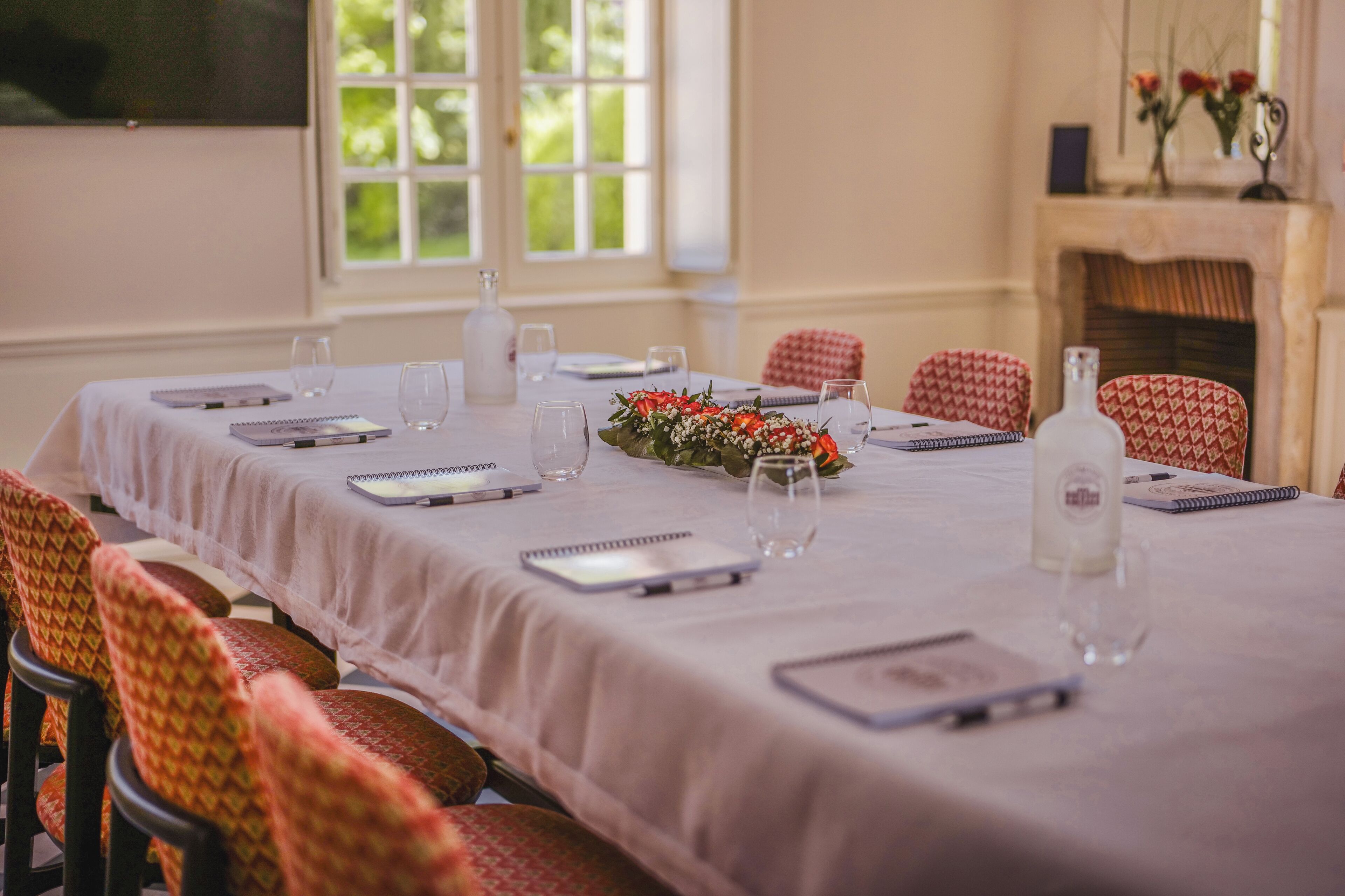 A dining room with a long table set for a meal, surrounded by patterned chairs.