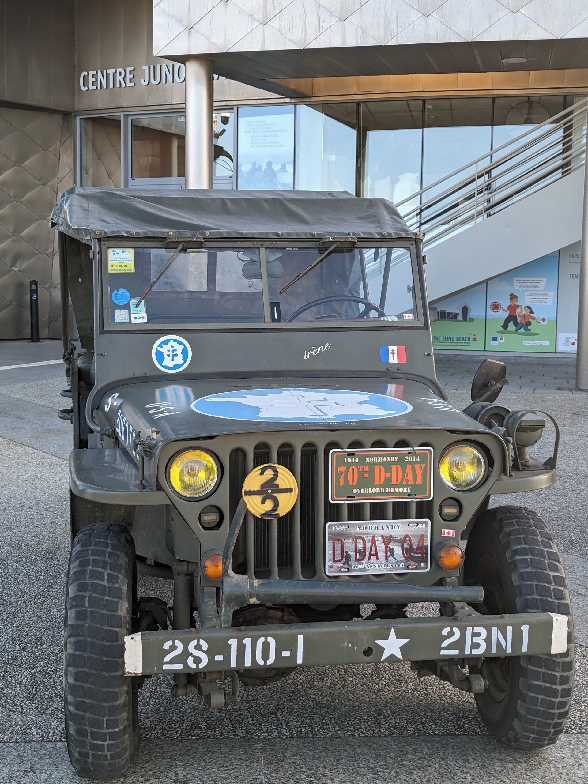 A military vehicle parked in front of a building with a sign reading "Centre Juno".