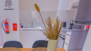 Una cocina compacta con lavamanos, estufa y comedor con sillas y mesa.