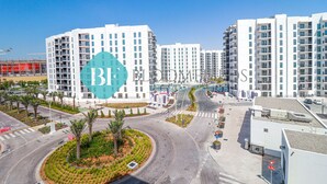 Un complejo de apartamentos moderno con varios edificios de gran altura, una glorieta y zonas ajardinadas con palmeras.