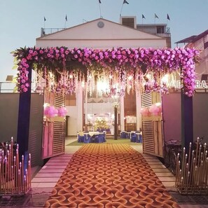 A reception area with a floral archway, a patterned carpet, and a seating area with tables and chairs. - Hotel Vibharaj Palace (Kanpur)