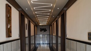 Un pasillo con suelo de mármol, paneles de madera e iluminación moderna.