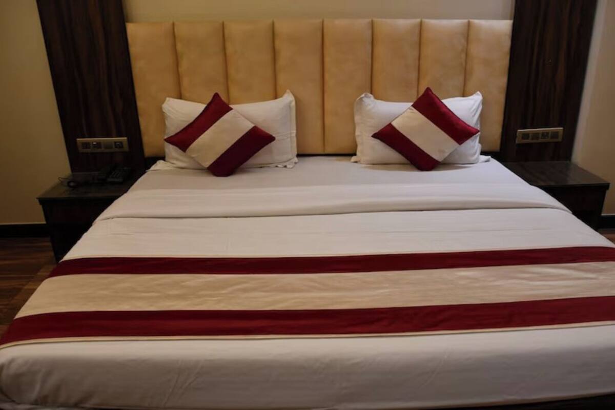 A hotel room with a large bed, two bedside tables, and a wooden floor.