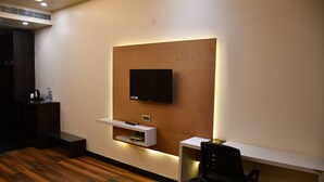 Una habitación moderna con un televisor de pantalla plana montado en una pared texturizada, una mesa consola blanca, una silla de oficina negra y suelo de madera.
