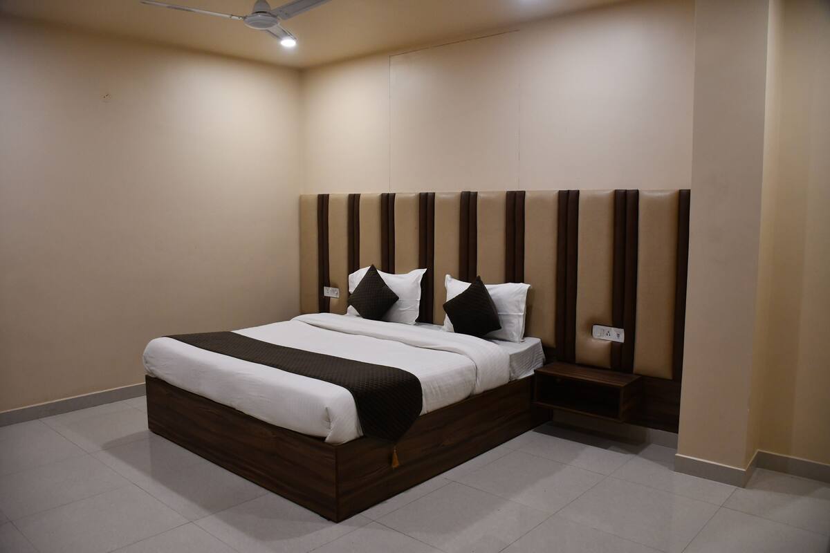 A modern bedroom with a large bed, a wooden headboard, and a bedside table.