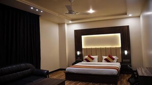 Una habitación de hotel con una cama grande, un ventilador de techo y una cortina oscura.