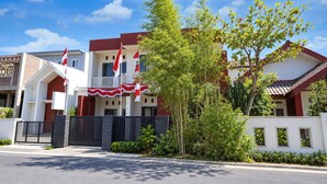 A two-story residential building with a balcony, a flag, and a tree in the foreground. - Hotel O Icha Homestay (Makassar)