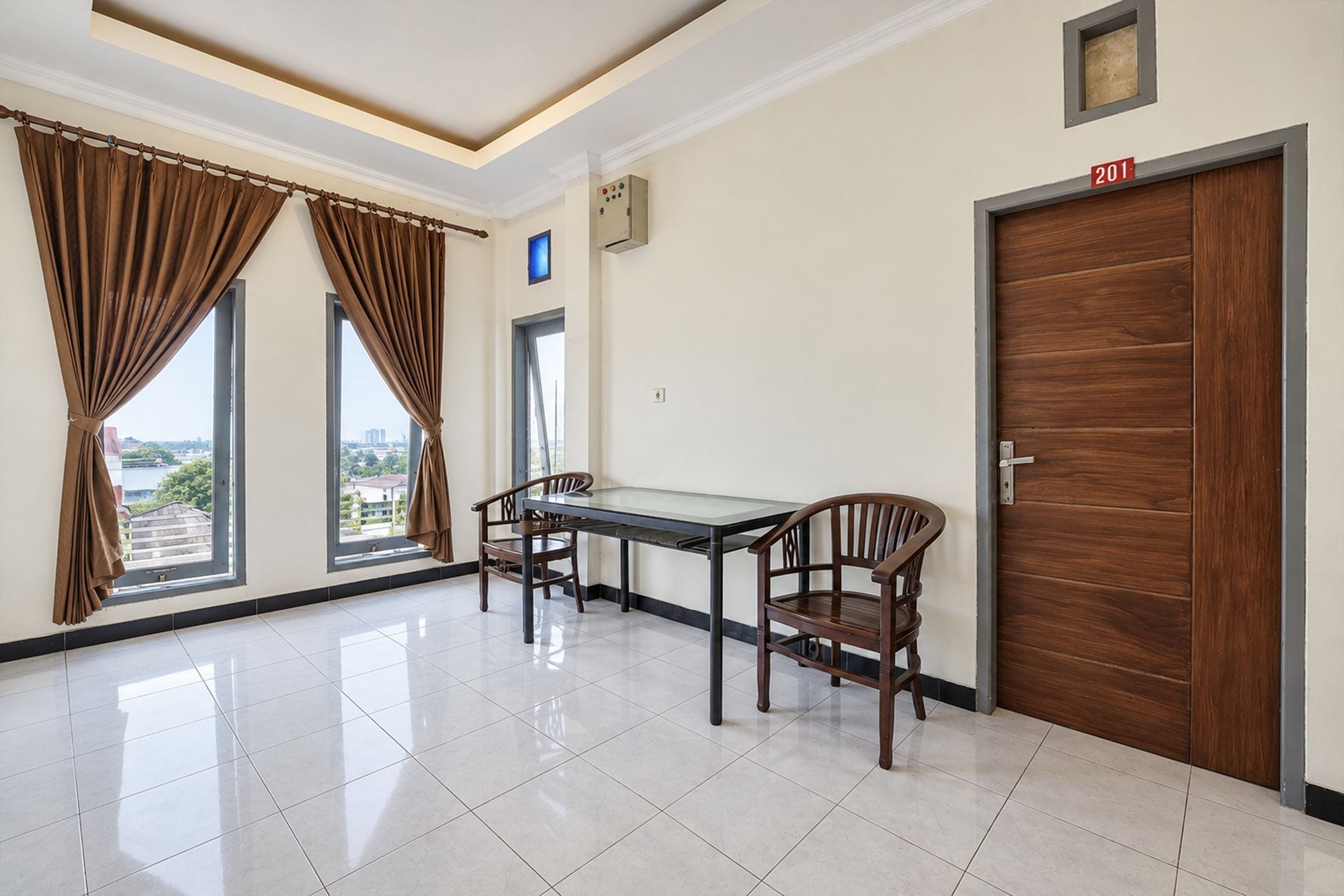 A room with a dining table and chairs, a wooden door, and a view through a window.
