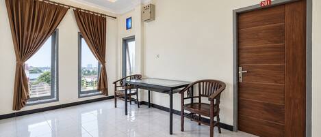 A room with a dining table and chairs, a wooden door, and a view through a window.