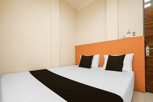 Habitación de hotel con cama, puerta de madera y termostato en la pared.