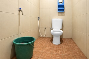Casa de banho pequena com sanita, um balde verde e um secador de mãos azul fixado na parede.