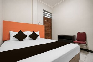 A hotel room with a bed, a red chair, a TV, and a wooden door. - Hotel O Icha Homestay (Makassar)