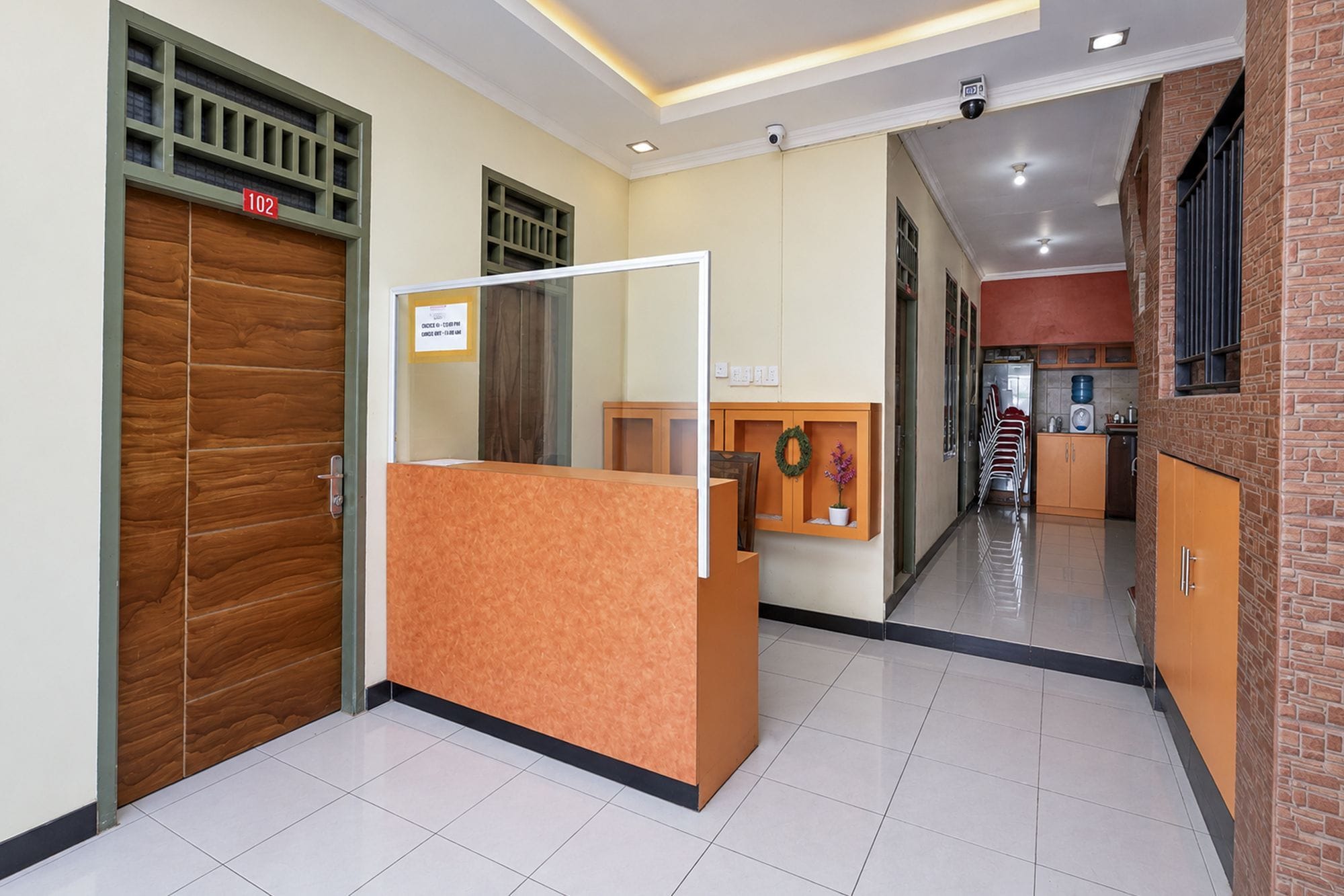 Un espace d’accueil doté d’une porte en bois, d’un comptoir de réception et d’un couloir menant à une cuisine.