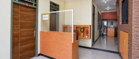 A reception area with a wooden door, a reception desk, and a corridor leading to a kitchen area.