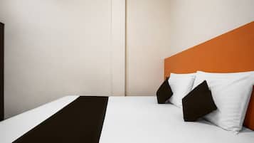 Una habitación de hotel con una cama, ropa de cama blanca, un plaid marrón y almohadas negras.
