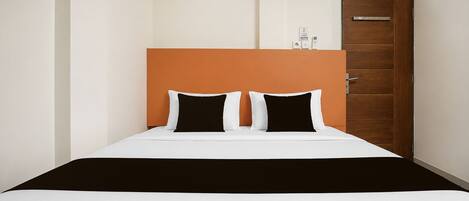 A hotel room with a bed, a wooden door, and a small window.