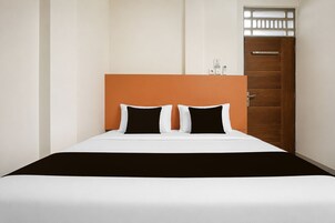 Una habitación de hotel con una cama, una puerta de madera y un ventanal pequeño.