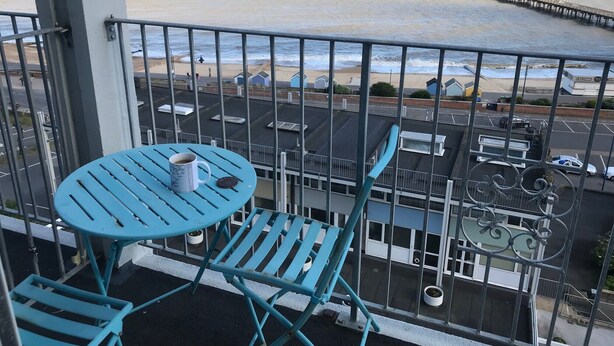 A balcony with a table and chairs, overlooking a beach and a pier. - Attractive apartment which has, possibly,  the best views in Felixstowe (Felixstowe)