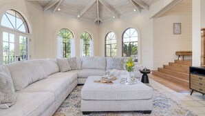 A spacious living room with a large sectional sofa, a coffee table, and a staircase leading to an upper level. - Pool, Firepit Lounge, Cornhole, and Outdoor Kitchen + Dining Area | Diamondback (Scottsdale)
