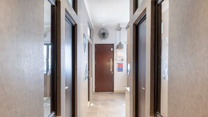 A hallway with a wooden door at the end, a ceiling fan, and a light fixture. - OYO Life 3246 Walnut Inn G-10 (Karawang)