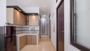 A modern kitchen with wooden cabinets, a refrigerator, and a tiled floor. - OYO Life 3246 Walnut Inn G-10 (Karawang)