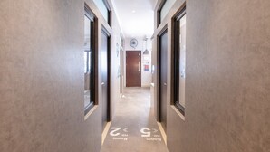 A hallway with two doors on each side, a ceiling fan, and a light fixture. - OYO Life 3246 Walnut Inn G-10 (Karawang)