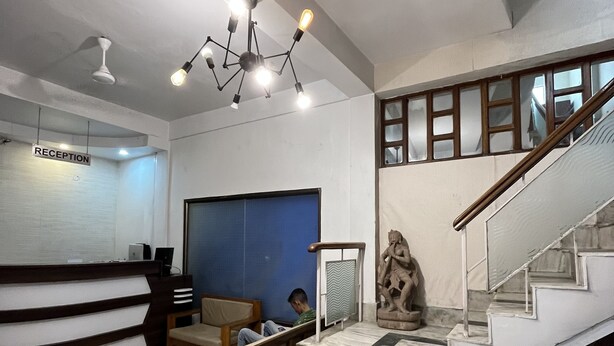 Un área de recepción con mostrador, asientos, una escalera y una escultura.