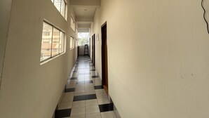 Un pasillo con suelo a cuadros, una escalera y un dispositivo fijado a la pared.