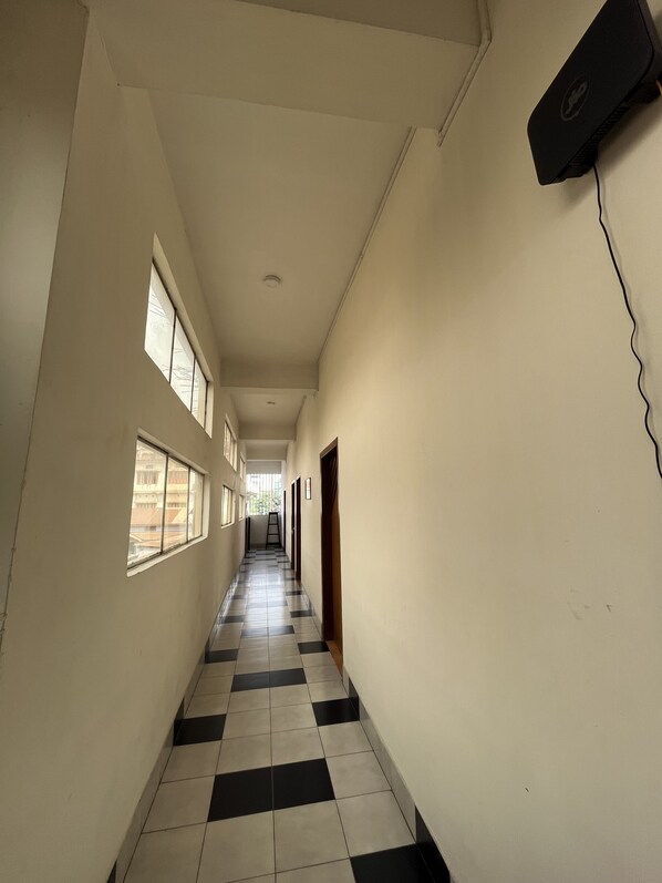 A corridor with checkered flooring, a ladder, and a wall-mounted device.