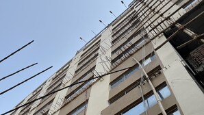 Un edificio de varios pisos con numerosas ventanas y cables eléctricos a la vista.