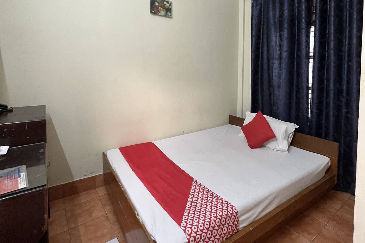 A bedroom with a single bed, a desk, and an air conditioning unit.
