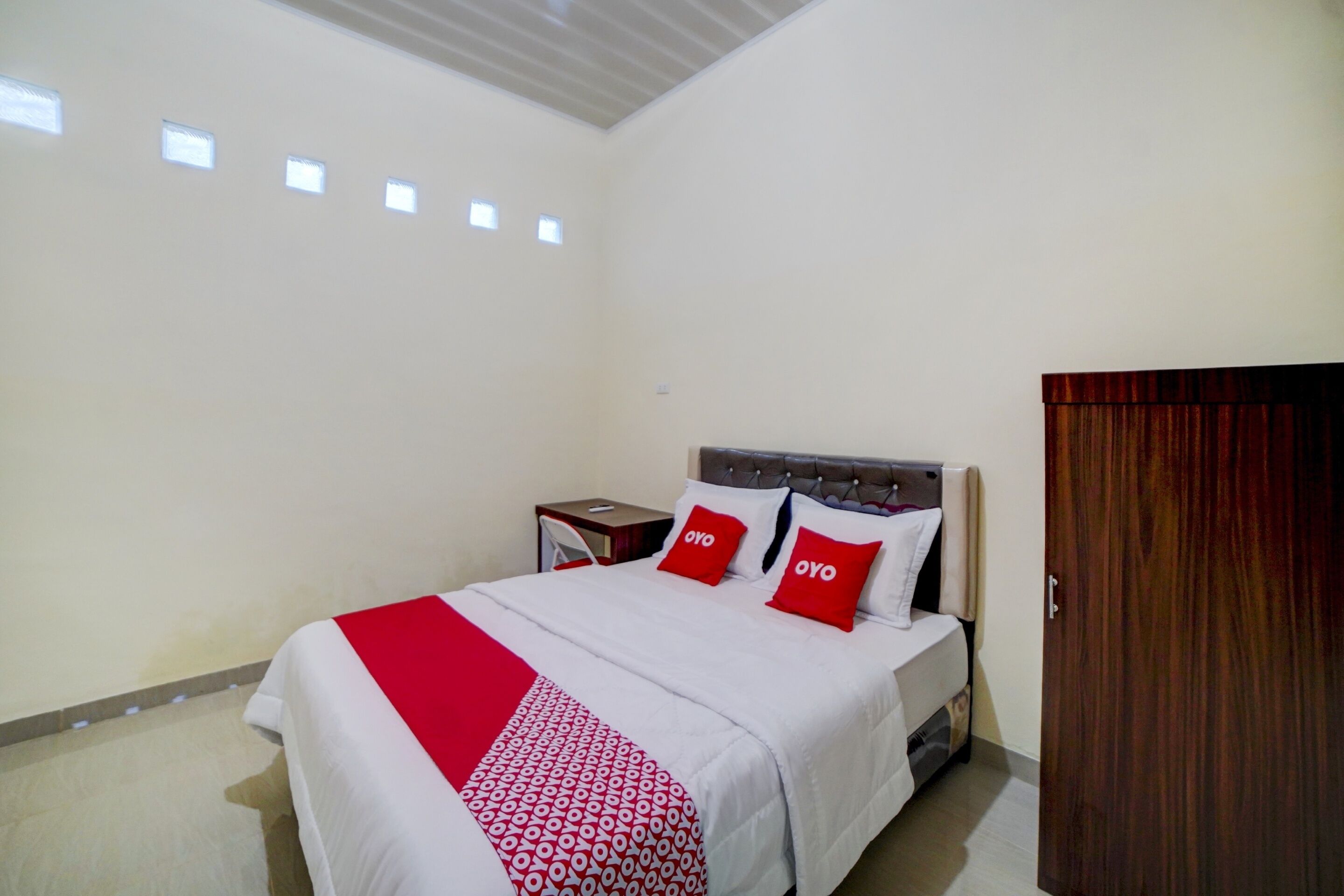 A hotel room with a bed, a nightstand, a wardrobe, and a ceiling with skylights.