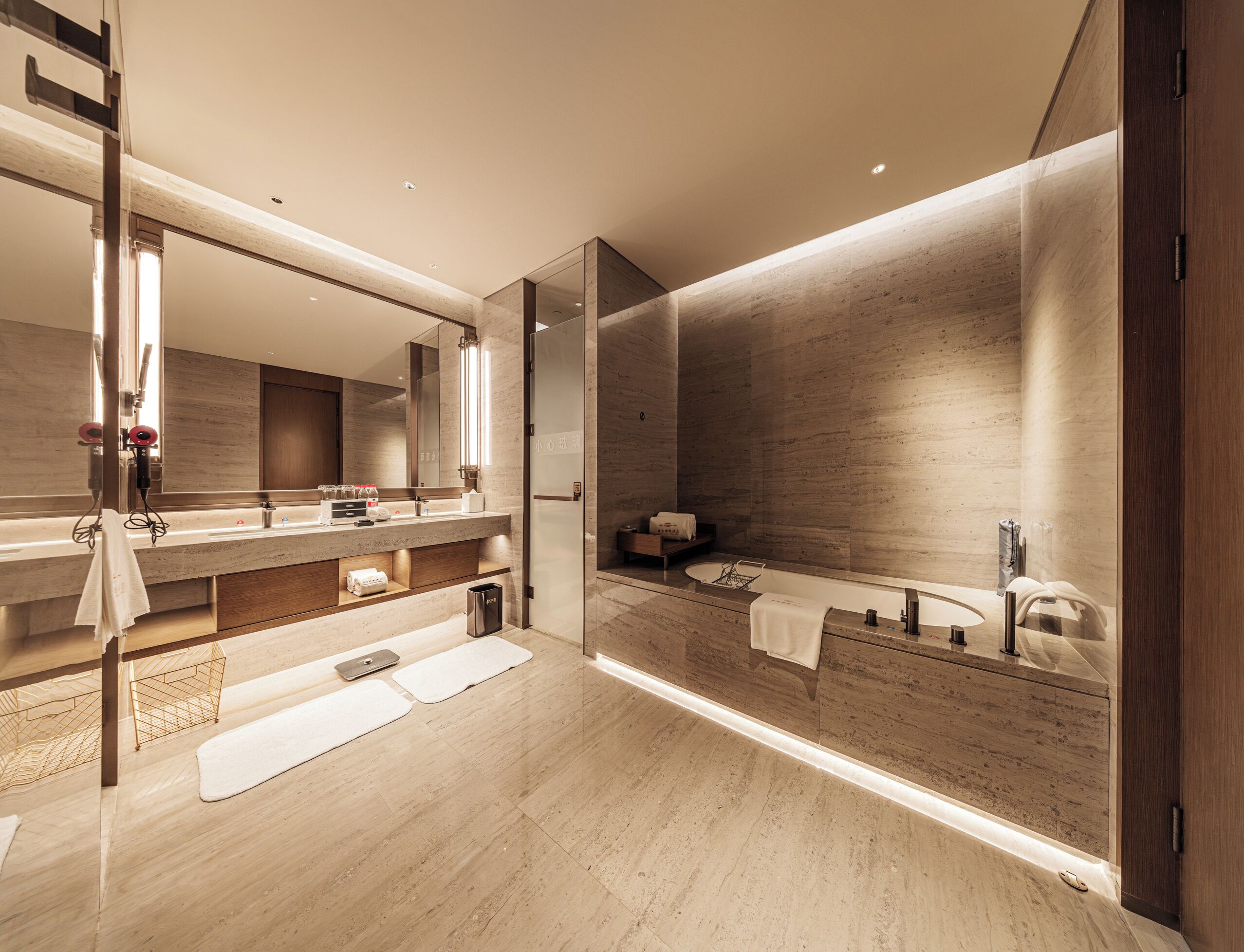 A modern bathroom with a large mirror, wooden vanity, and a walk-in shower.