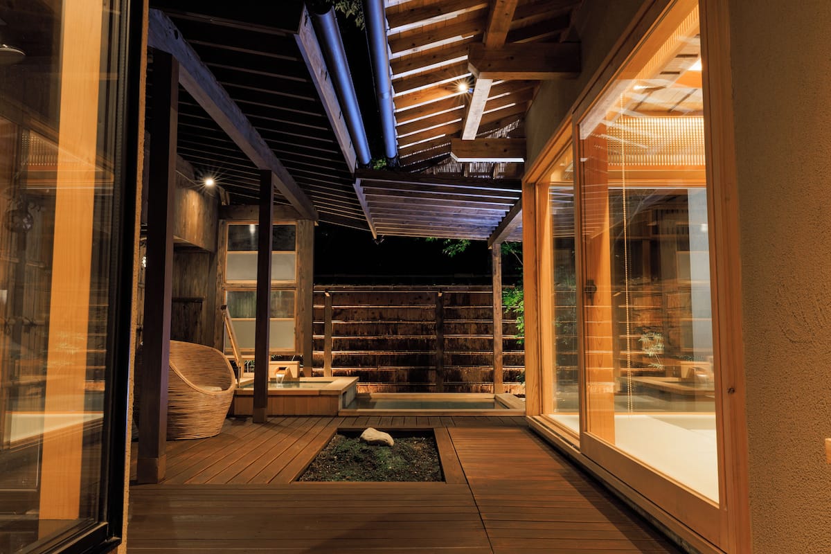 A modern interior with a wooden deck, a stone feature, and a glass door leading to a balcony.