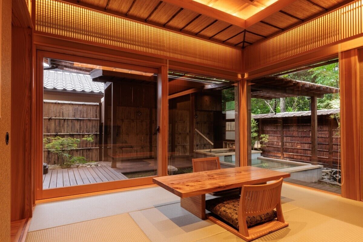 A traditional Japanese-style room with tatami flooring, a wooden table, and sliding doors leading to an outdoor area with a wooden deck and a small pool.
