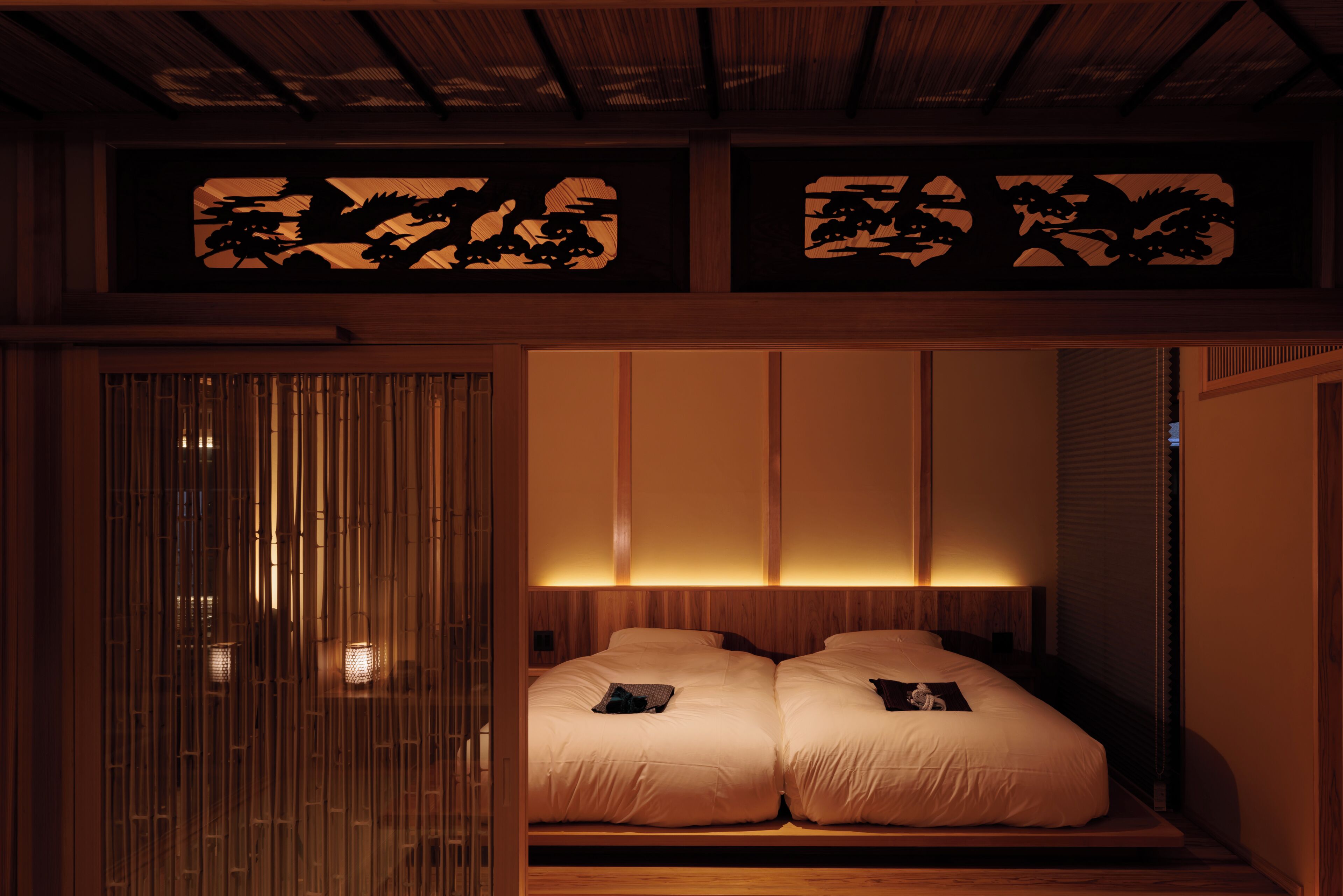 Ein traditioneller japanischer Raum mit Tatami-Boden, einem niedrigen Holzbett und Schiebetüren mit dekorativer Füllung.