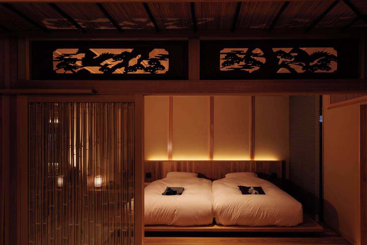 A traditional Japanese-style room with tatami flooring, a low wooden bed, and sliding doors with a decorative panel.