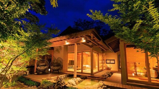 Une maison moderne dotée d’une terrasse en bois, d’un bassin à carpes koï et d’un patio vitré.