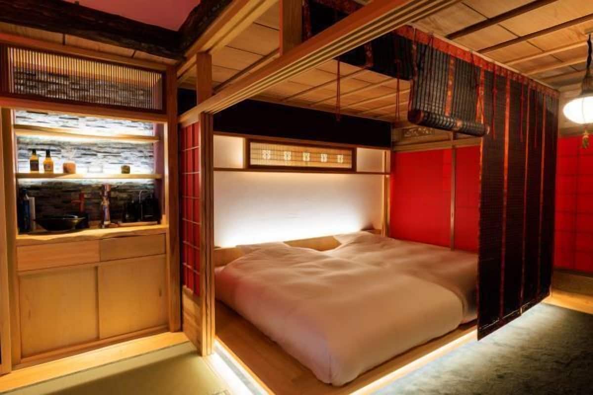 A traditional Japanese-style room with a bed, a wooden cabinet, and a red wall.