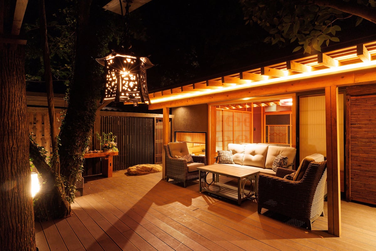 An outdoor patio with wooden flooring, wicker furniture, and a hanging lantern.