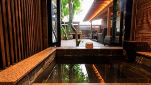 Un jardin intérieur paisible, agrémenté d’une fontaine en pierre, de bancs en bois et d’une clôture en bois.
