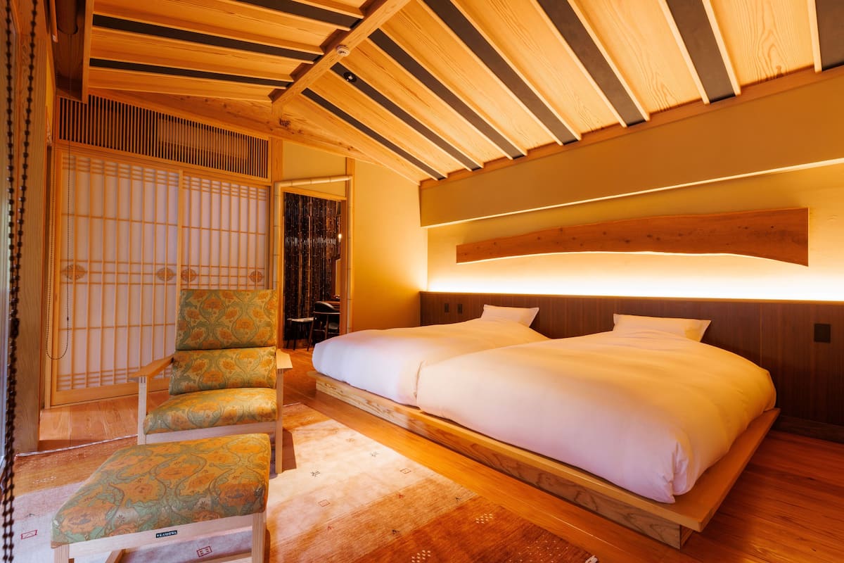 A traditional Japanese-style room with tatami flooring, a low platform bed, and a shoji screen.